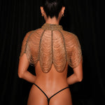 Person wearing a sheer gold top against a black background