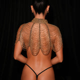 Person wearing a sheer gold top against a black background