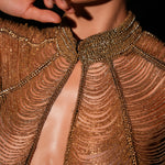 Close-up of a person wearing a gold beaded outfit with a blurred background