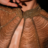 Close-up of a person wearing a gold beaded outfit with a blurred background