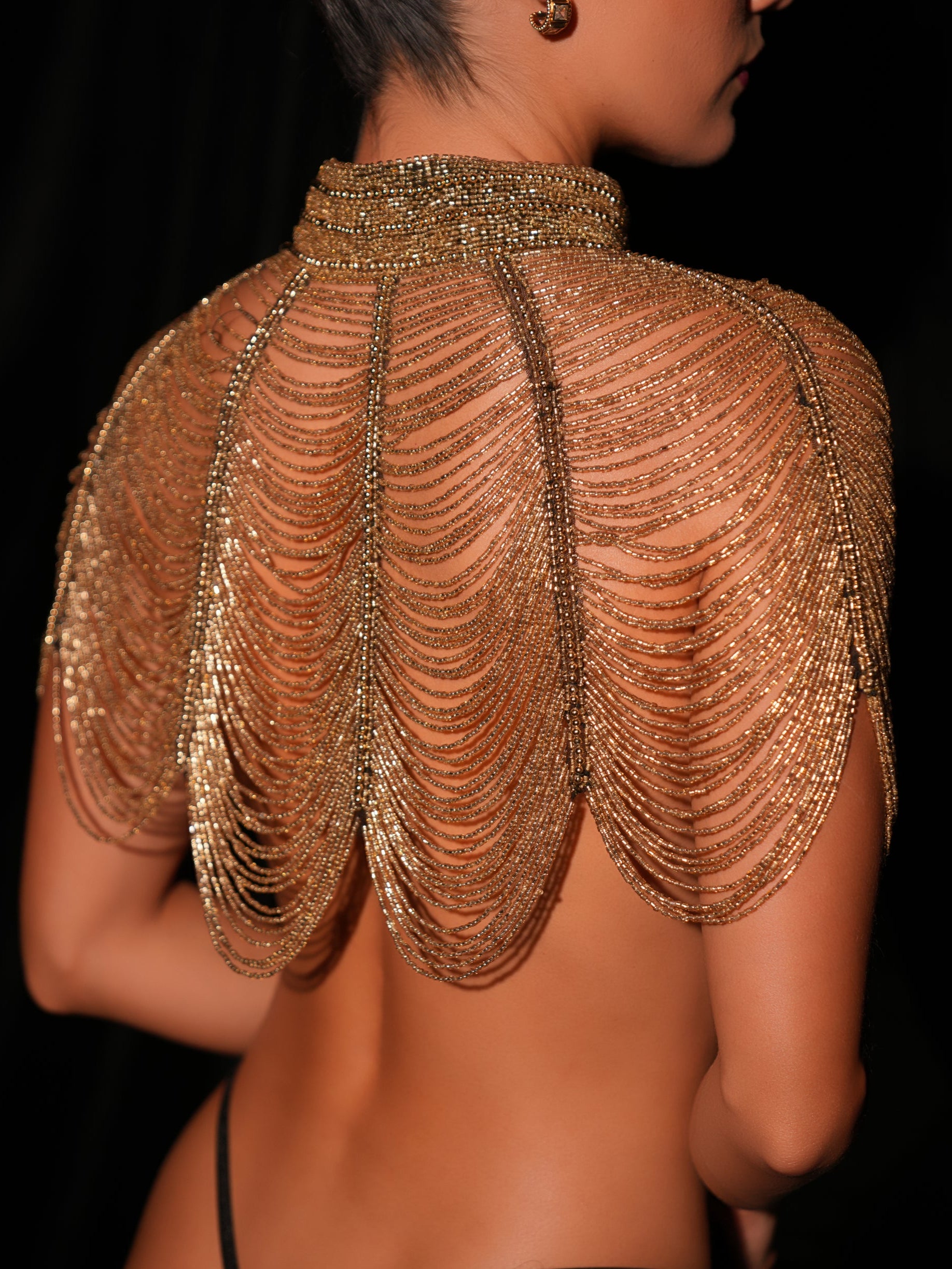 Gold beaded shoulder piece on a black background